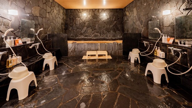 A stone-walled bathroom with multiple sinks, mirrors, and toiletries. - Hotel Grand Terrace Obihiro (Obihiro)