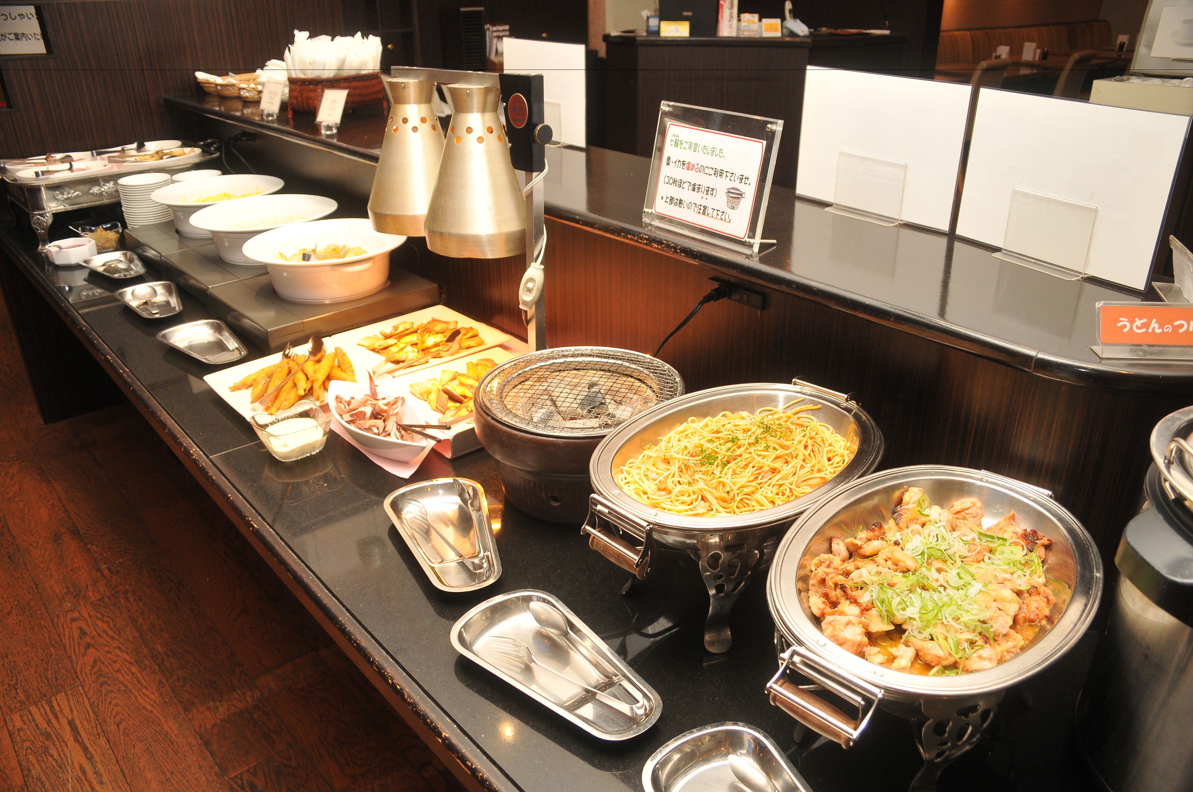 Un buffet proposant une variété de plats, notamment des pâtes, des salades et des plats frits.