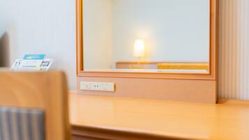 Una habitación de hotel con un escritorio de madera, un espejo y una lámpara.