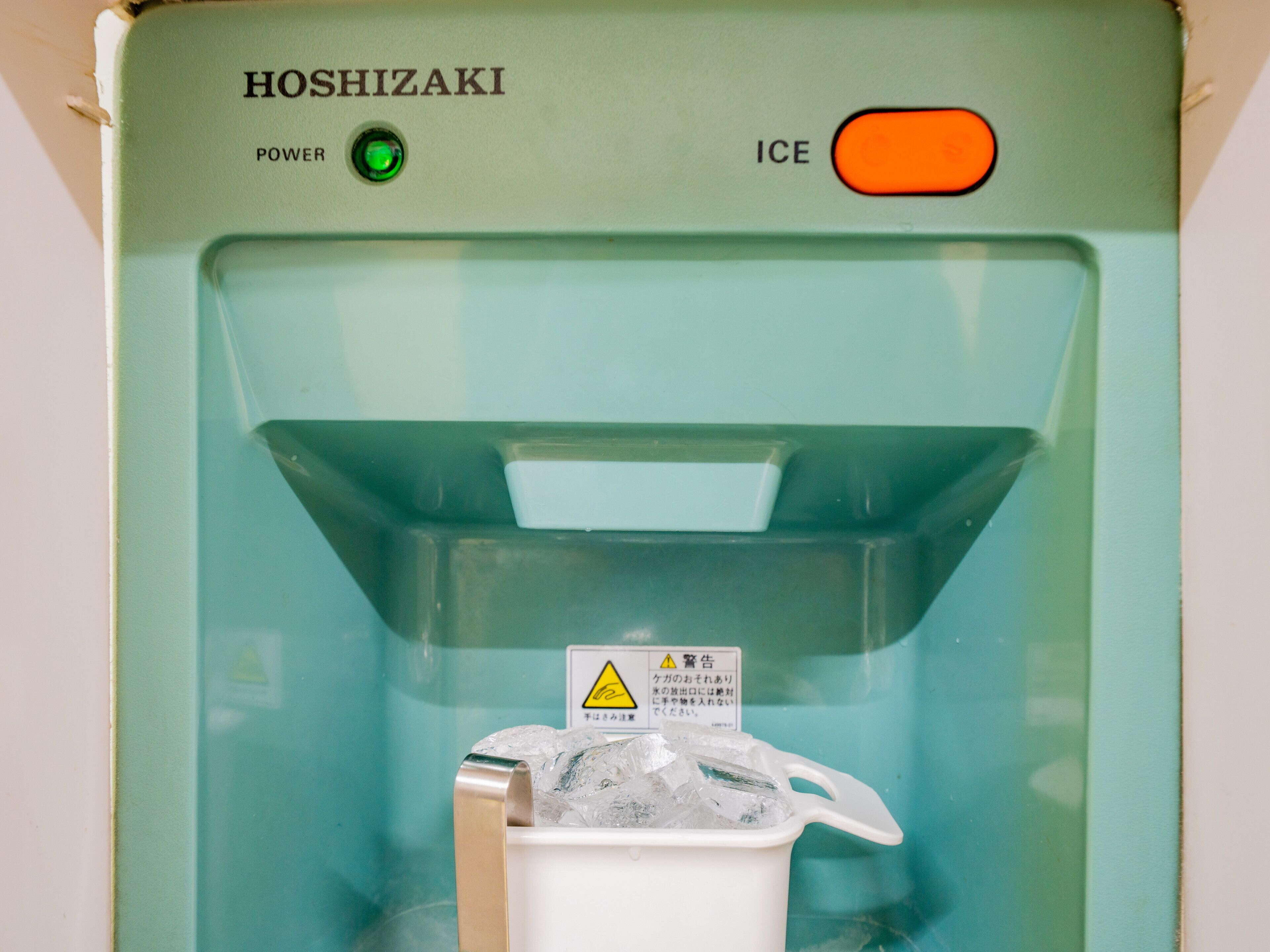 En Hoshizaki ismaskine med advarselsmærke og en grøn tændknap.