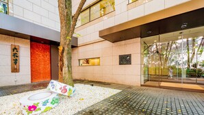 A modern building entrance with a tree, a flower arrangement, and a tiled floor. - Hotel Grand Terrace Obihiro (Obihiro)