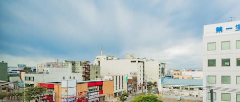 A cityscape with various buildings, including a white building with blue signage and a red building with a signboard.