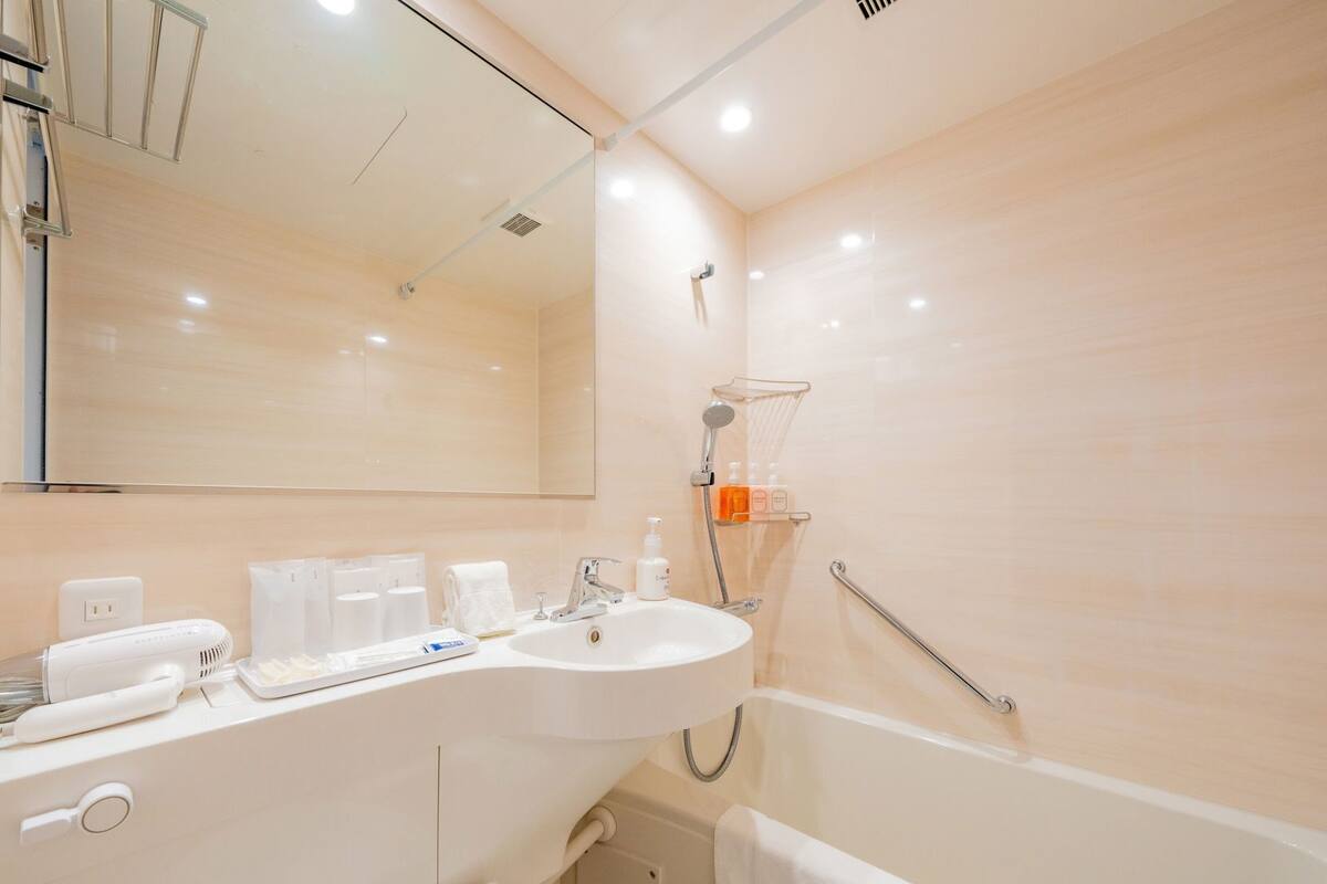 A modern bathroom with a sink, mirror, and shower.