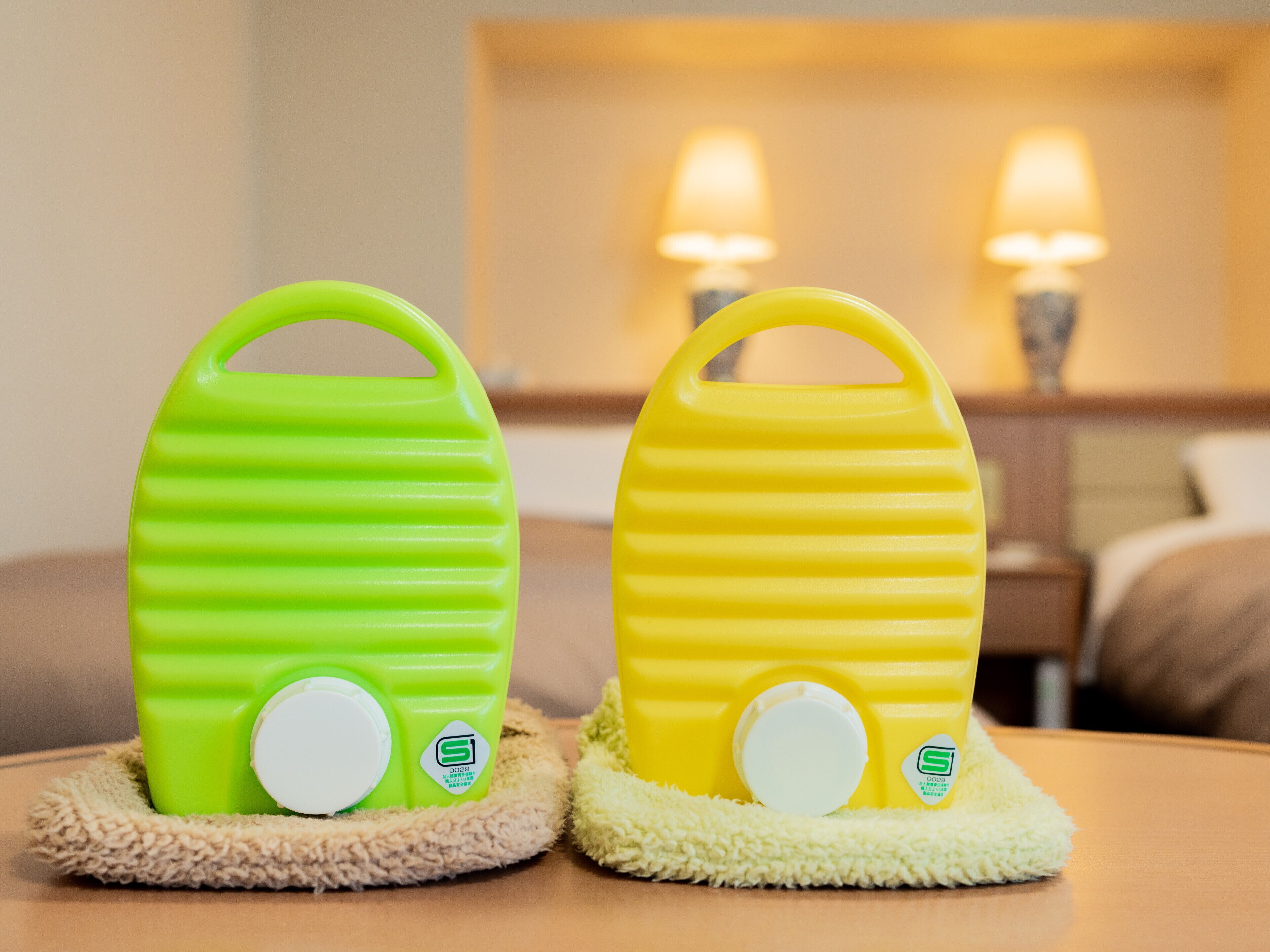 Two pet bowls on a table with a lamp in the background.