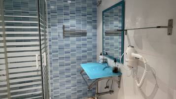 Un baño con cabina de ducha de vidrio, un lavamanos azul y un secador de pelo montado en la pared.