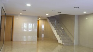 Un interior espacioso con piso pulido, una puerta de madera y una escalera con barandales de metal.