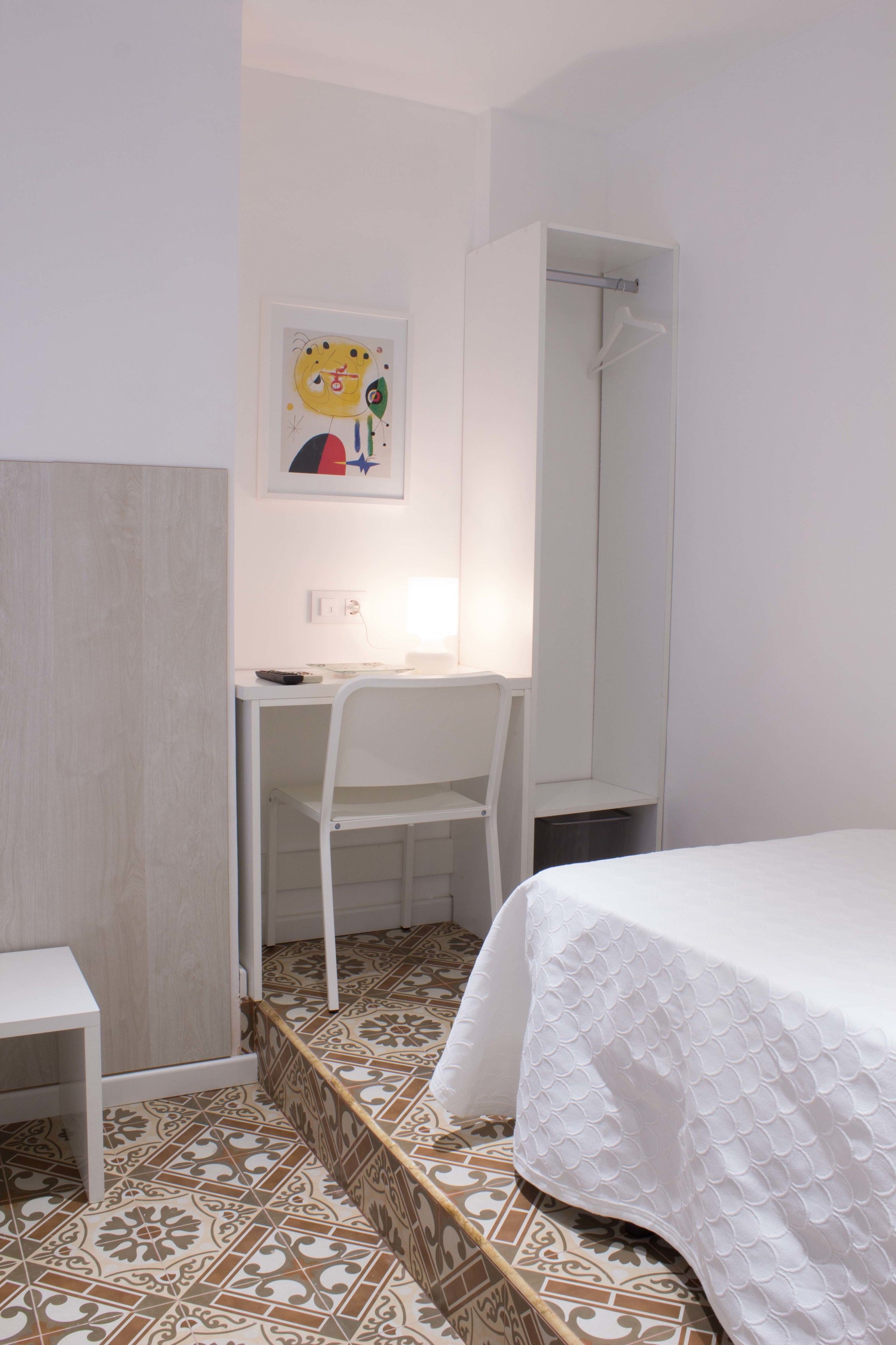 Un dormitorio con cama, escritorio, silla y armario.