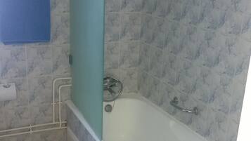 Un baño con bañera, un perchero para toallas y un dispensador de papel higiénico en la pared.