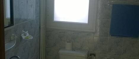 Un baño con inodoro, lavamanos y ventana.