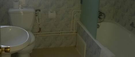 Une petite salle de bain avec des toilettes, un lavabo et une baignoire.