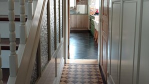 A hallway with a checkered floor, white walls, and a wooden staircase. - B&B Emma (Bruges)