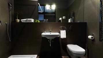 Un baño moderno con ducha, lavamanos e inodoro.
