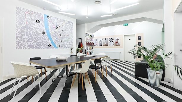 A modern conference room with a large map on the wall, a long table with chairs, and a striped floor. - MGZN Basilica Rooms (Budapest)