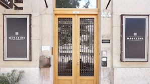 A wooden double door with a sign above it and two large signs on either side. - MGZN Basilica Rooms (Budapest)