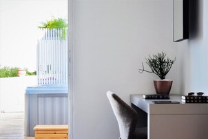 A modern room with a desk, chair, and a view of a balcony with plants.