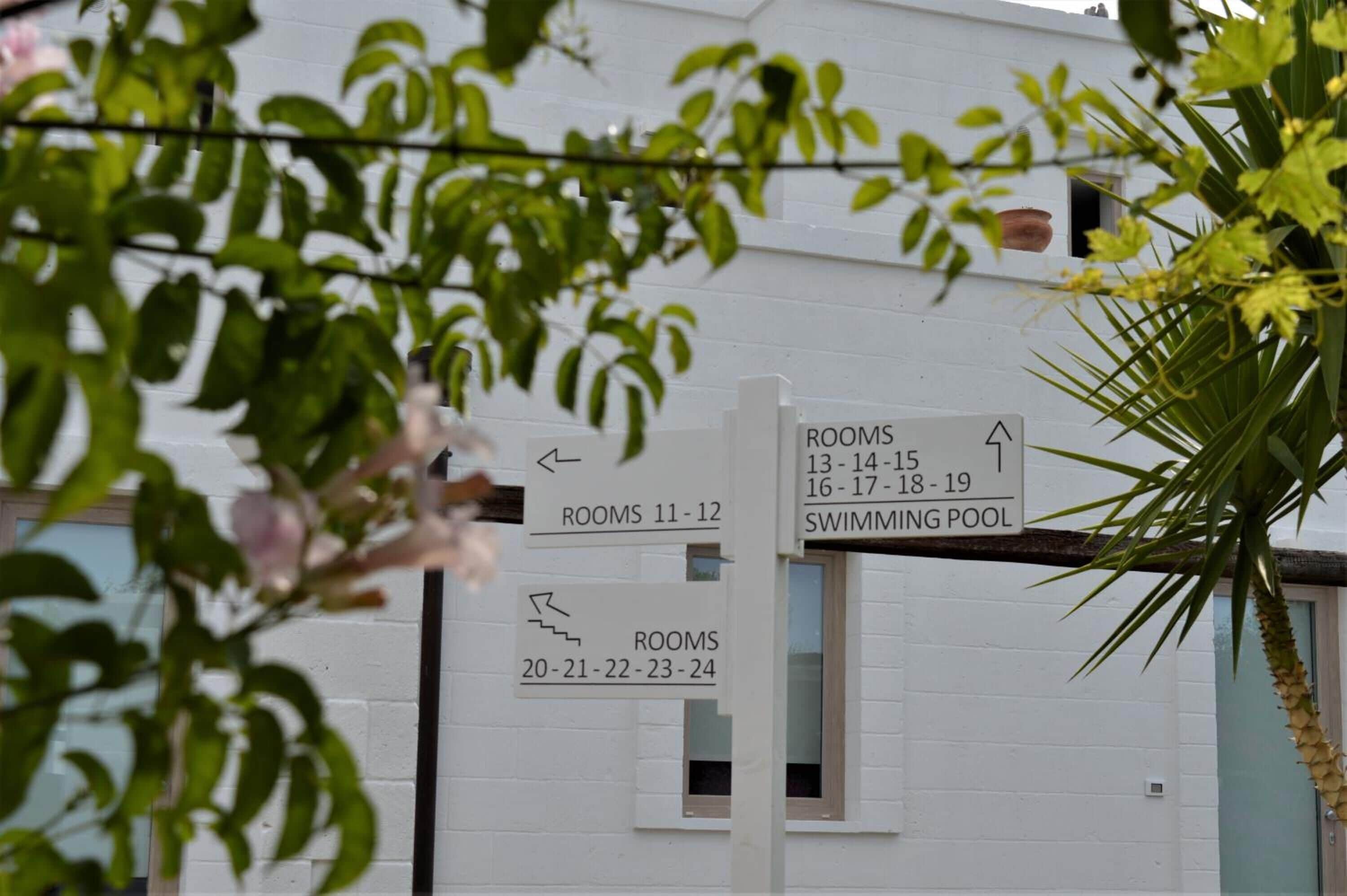 A building with signs indicating room numbers and a swimming pool.