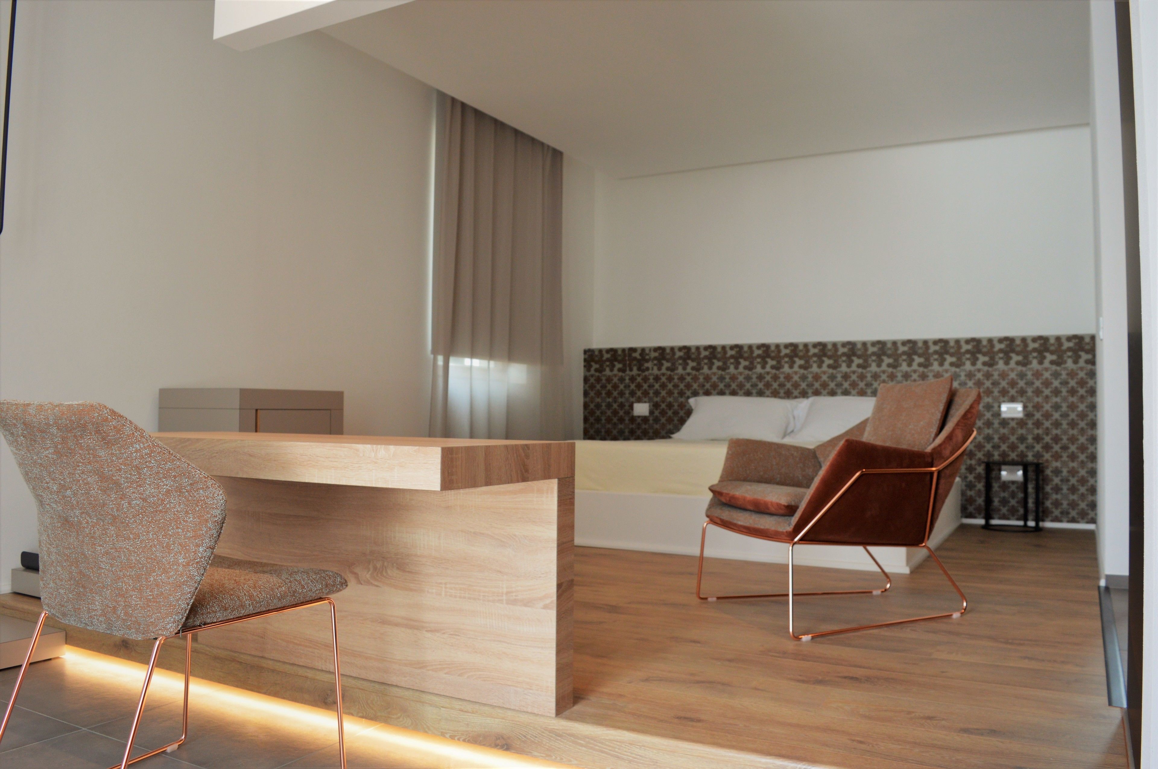 Un soggiorno moderno con un tavolino in legno, due poltrone, una divano e una parete decorata.