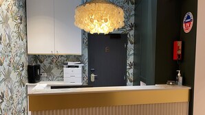Un mostrador de recepción de diseño moderno, una lámpara decorativa encima y una puerta con cerradura.