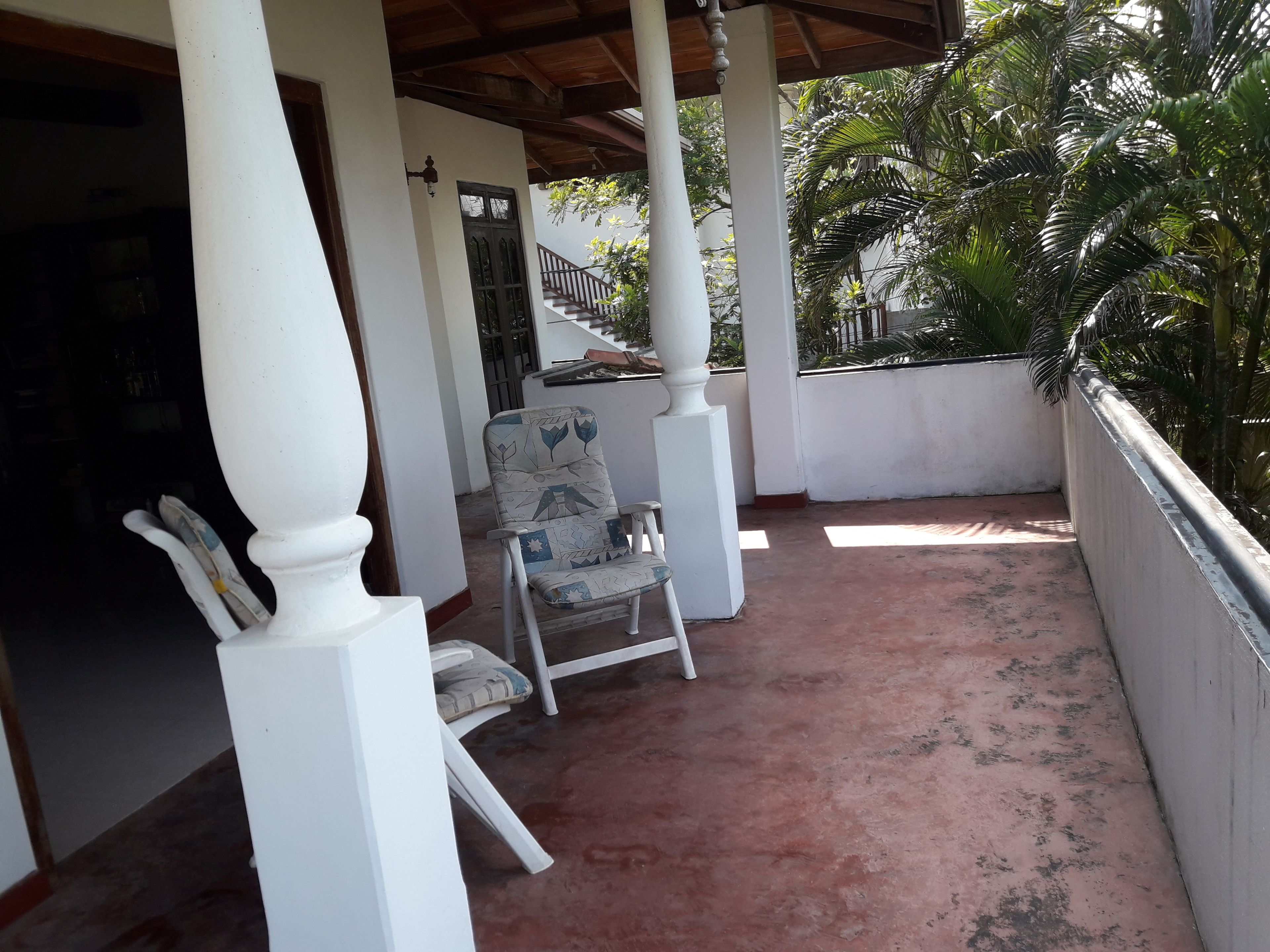 Un espacio al aire libre cubierto con barandilla blanca, una silla y una mesa.