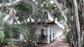 A covered outdoor area with a pathway leading to a building with a white facade and a porch. - Sea Front Hikkaduwa (Hikkaduwa)