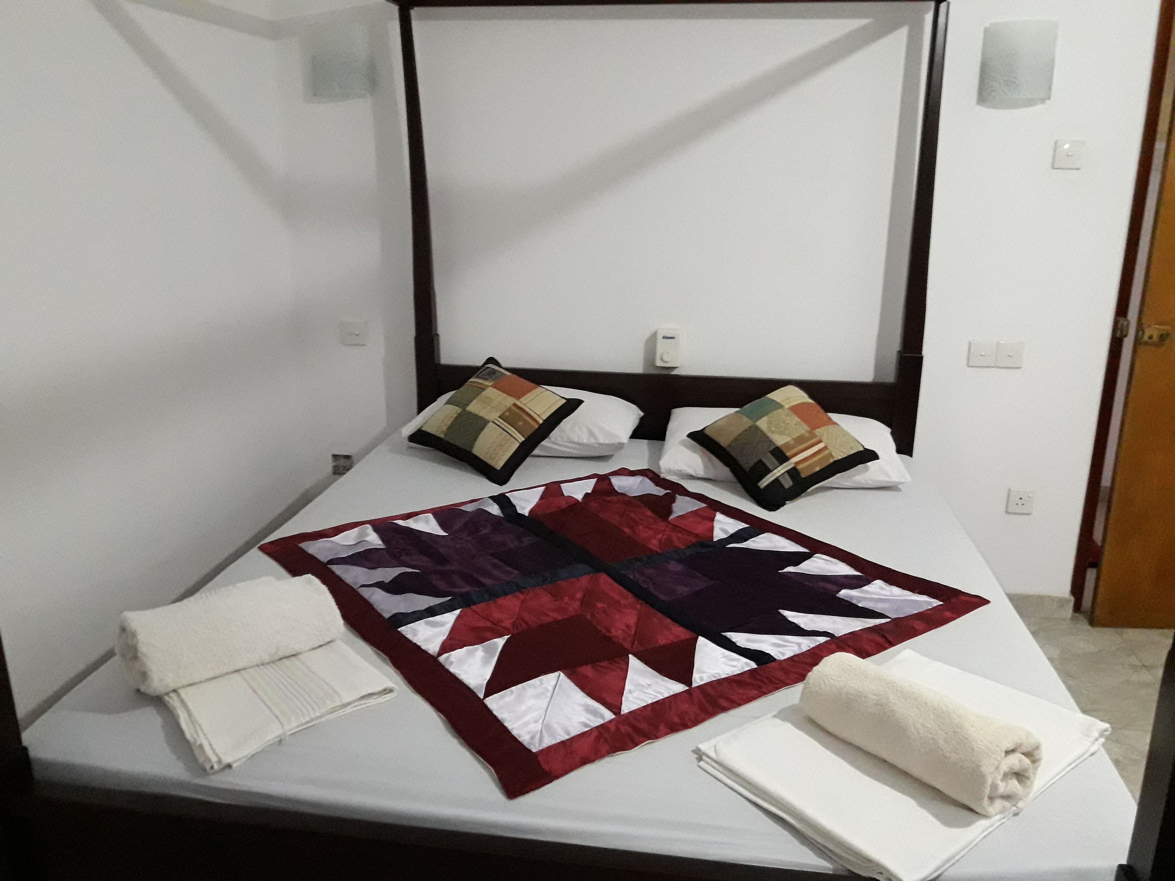 Una cama con colcha, almohadas y toallas.