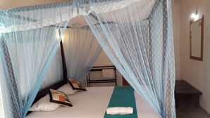 A single bed with a canopy, a bedside table, and a nightstand. - Sea Front Hikkaduwa (Hikkaduwa)