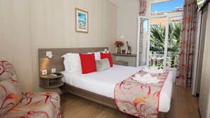 Habitación de hotel con cama, dos mesitas de noche, cortinas y vistas a zonas verdes.