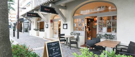 A hotel exterior with outdoor seating and a café.