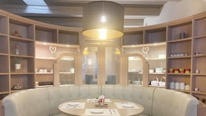 Una mesa redonda con mantel blanco, rodeada por un banco acolchado blanco.