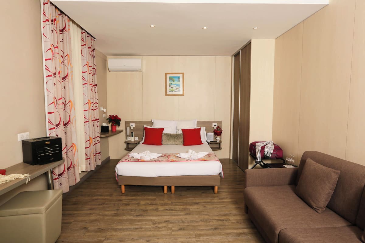 Ein Hotelzimmer mit Bett, Sofa, Schreibtisch und Fenster.