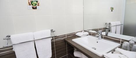 A modern bathroom with a large mirror, a sink, and a towel rack.