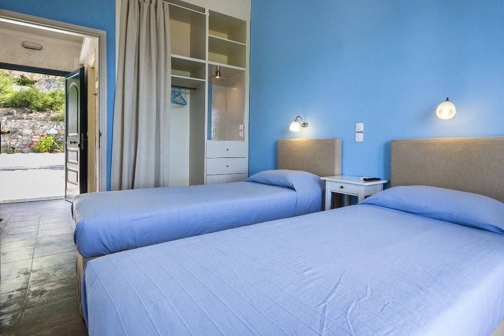 A room with two beds, a wardrobe, a desk, and a nightstand.