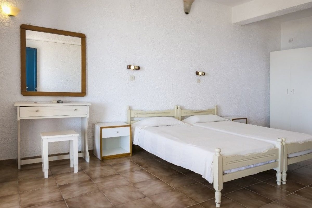 A bedroom with a bed, bedside tables, a dresser, and a mirror.