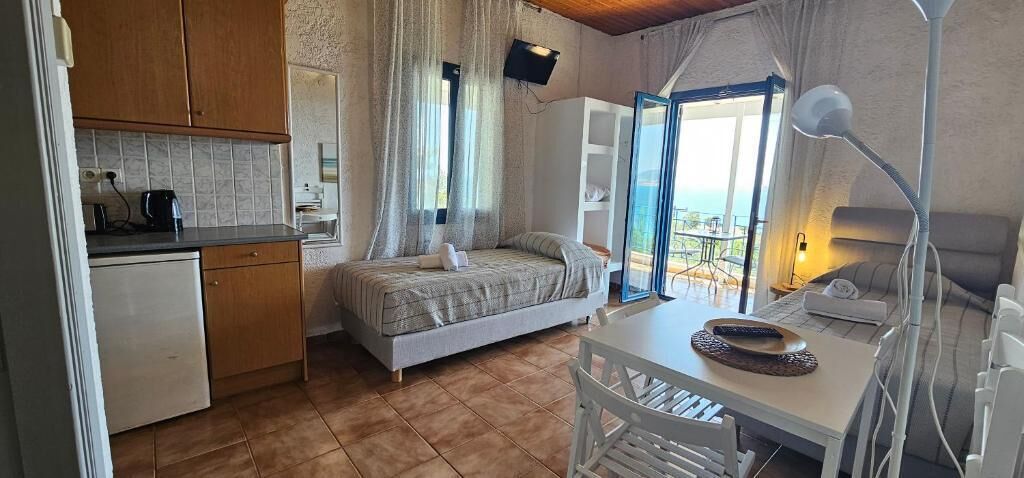 A bedroom with a bed, a bedside table, a desk, a chair, a window, and a view of the outdoors.