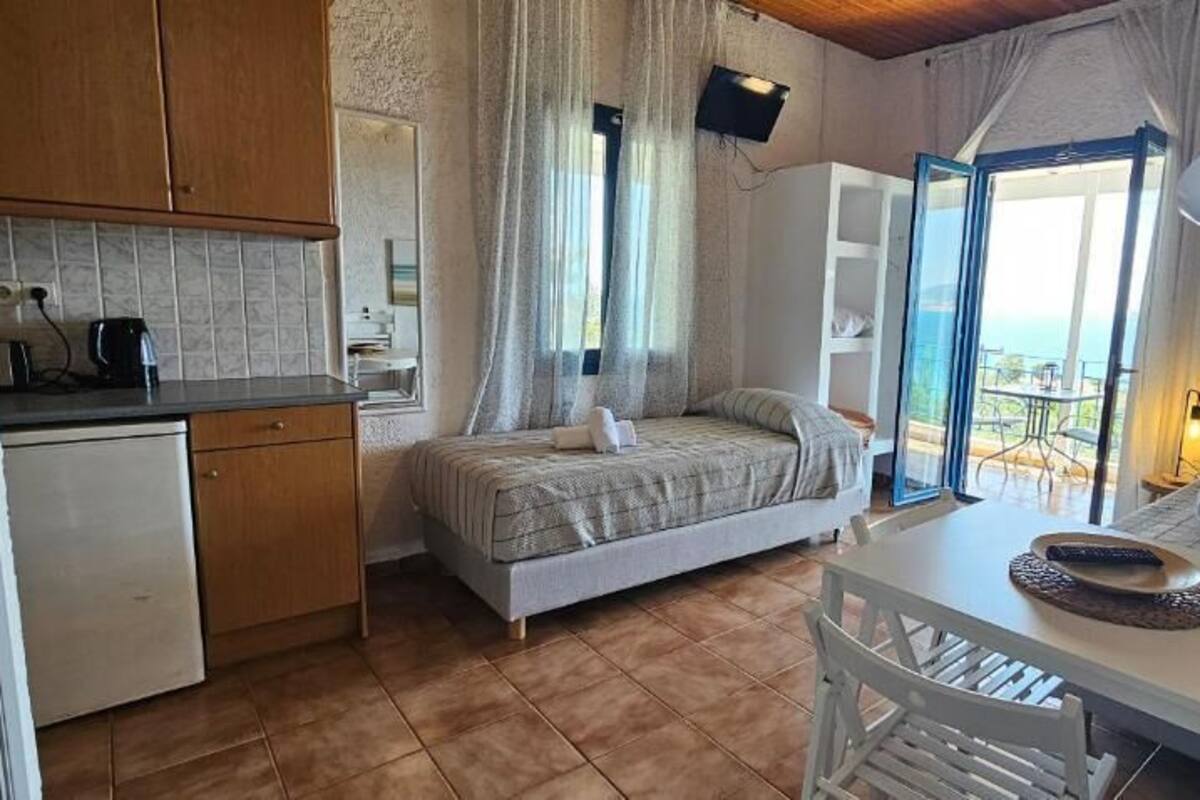 A bedroom with a bed, a bedside table, a desk, a chair, a window, and a view of the outdoors.