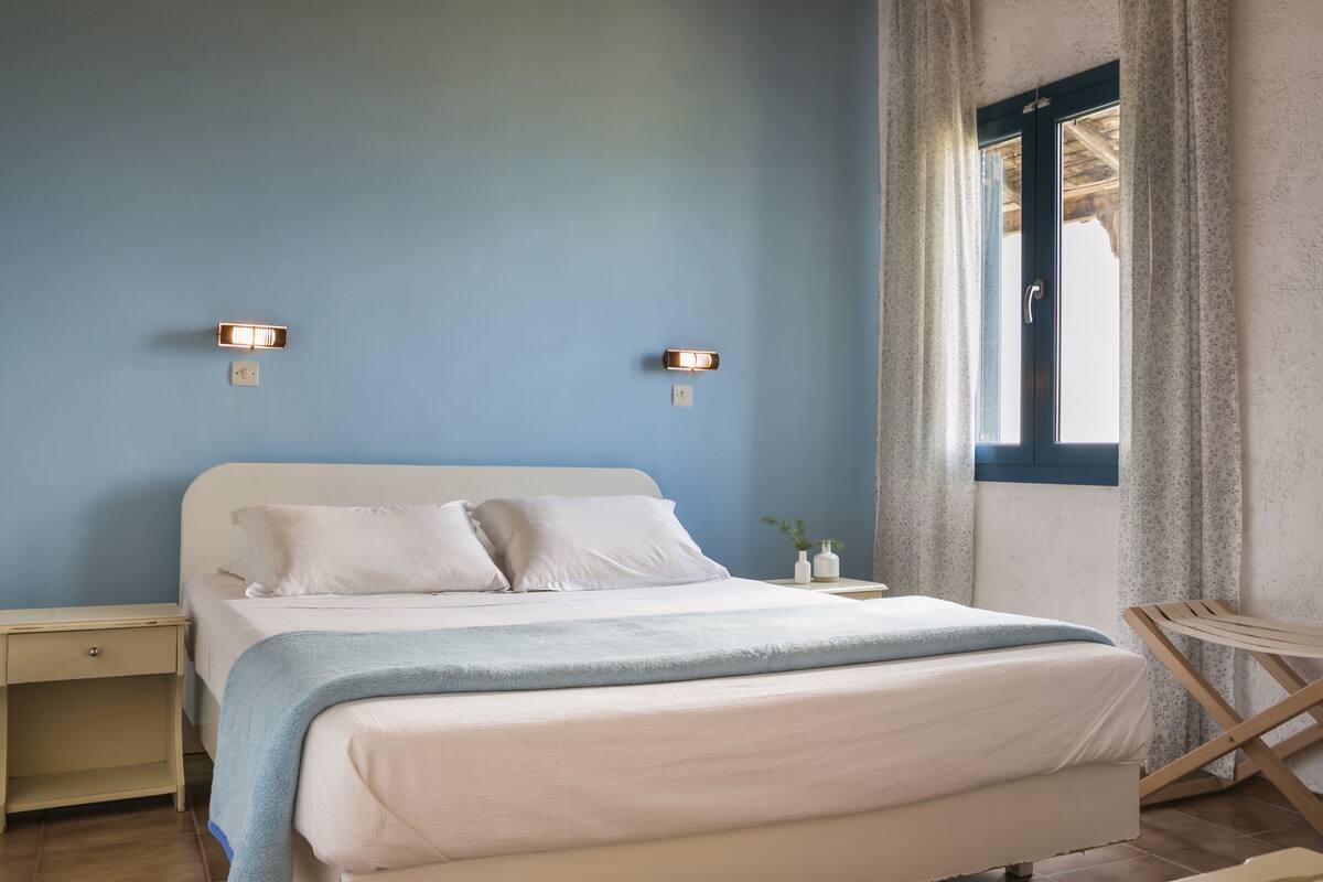 A bedroom with a bed, bedside tables, and a window with curtains.