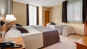 Una habitación de hotel con dos camas, un escritorio y un teléfono, y una puerta.