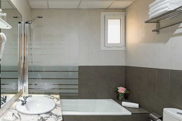 A modern bathroom with a glass shower enclosure, a white sink, and a large bathtub.