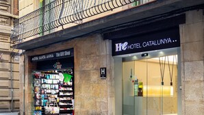 Fachada de hotel con un balcón y una tienda en la planta baja, con banderas.
