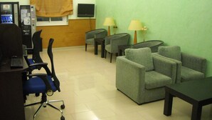 Una habitación con escritorio, computadora, sillas y televisor.