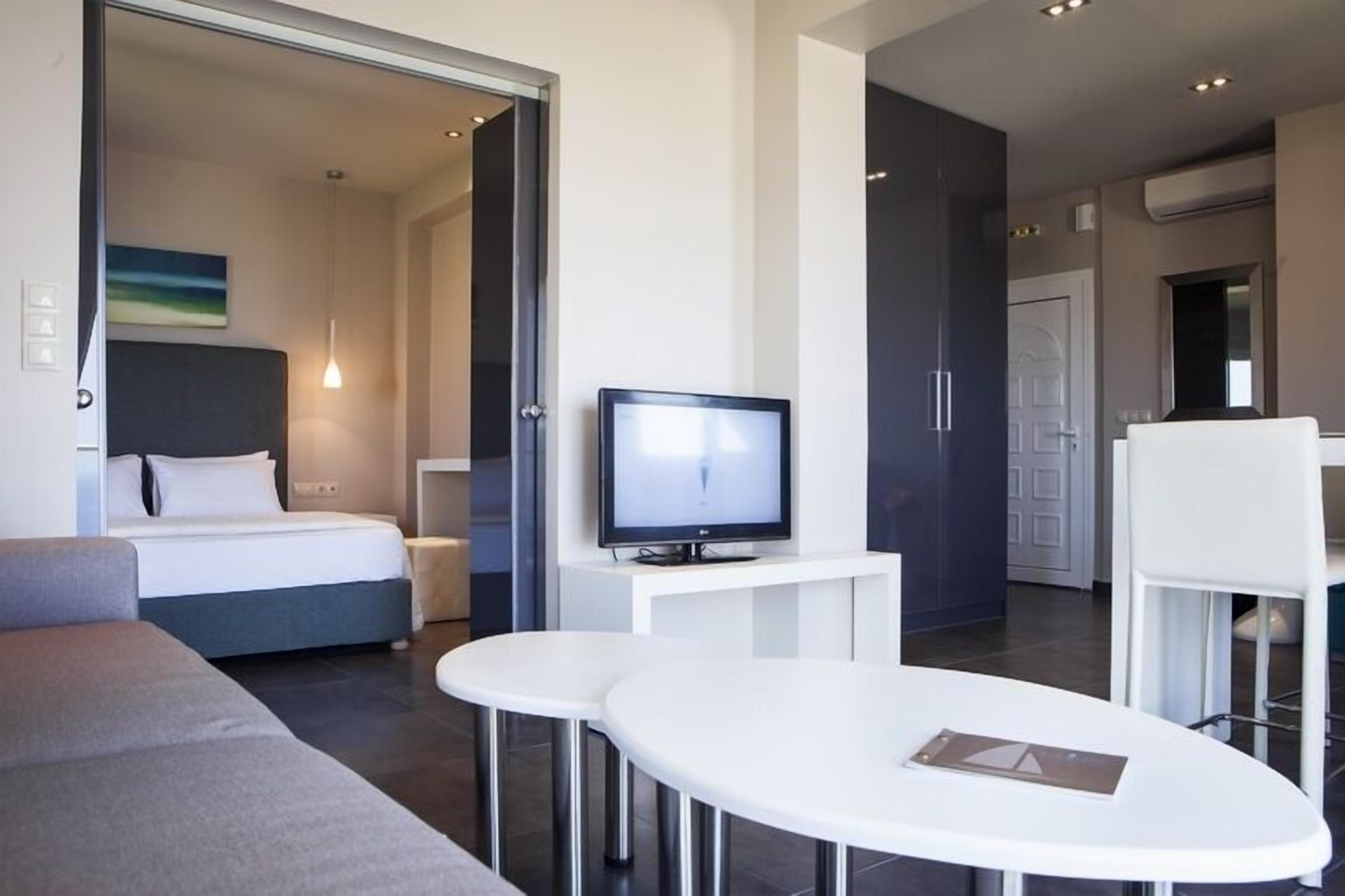 Een moderne hotelkamer met een bed, een televisie, een eettafeltje en een bank.