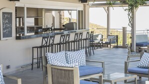 Een terras met barkrukken, comfortabele stoelen en een bar.