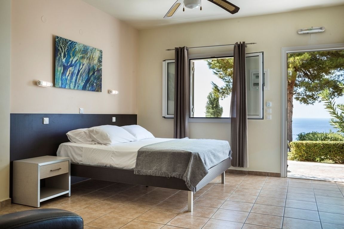 Un dormitorio con cama, mesita de noche y vistas al exterior.