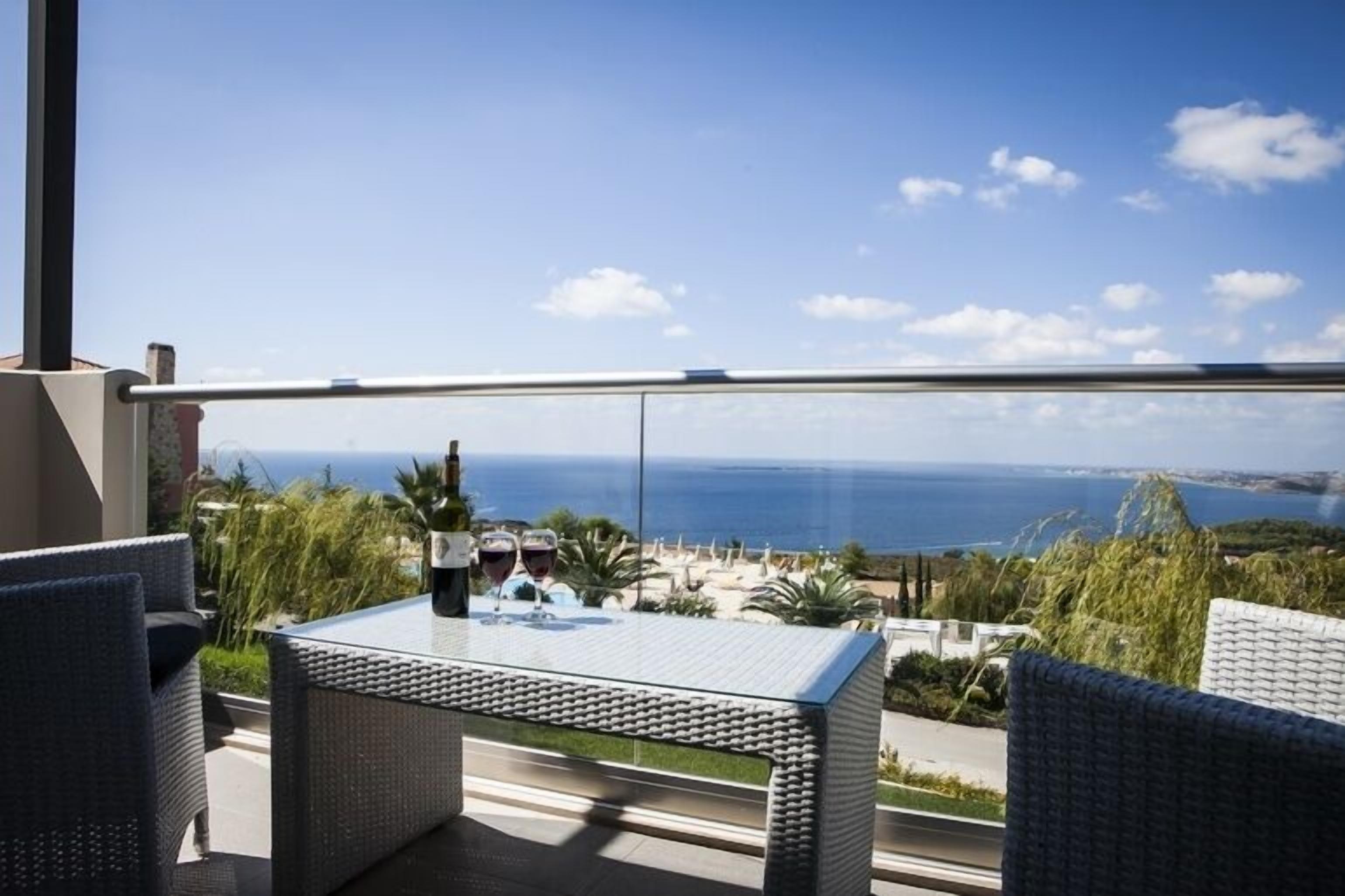 Un balcón con muebles de mimbre y una mesa, con vistas a la costa.