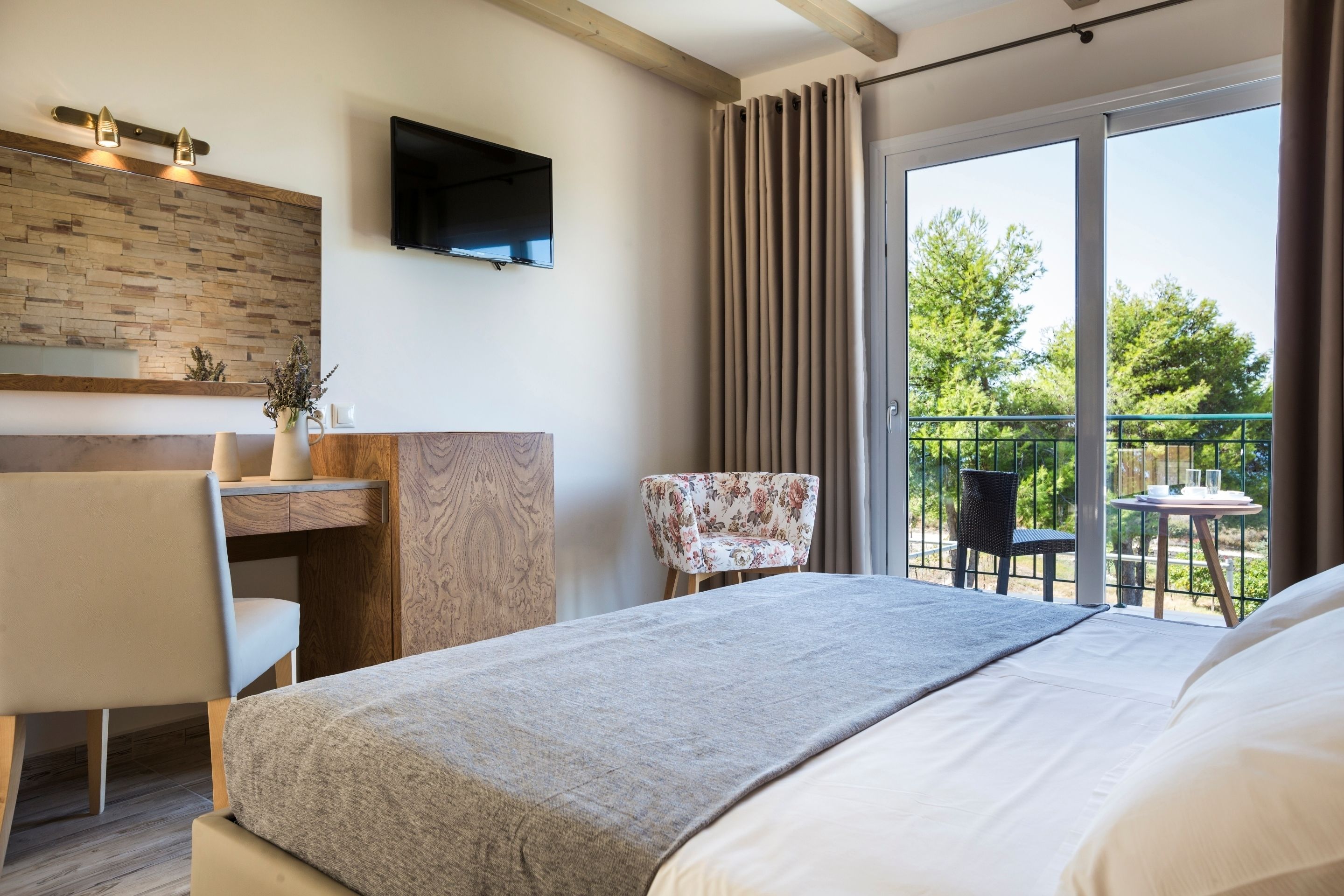 Une chambre d’hôtel moderne dotée d’un grand lit, d’un bureau avec une chaise, d’une télévision à écran plat et d’un balcon avec des meubles d’extérieur.