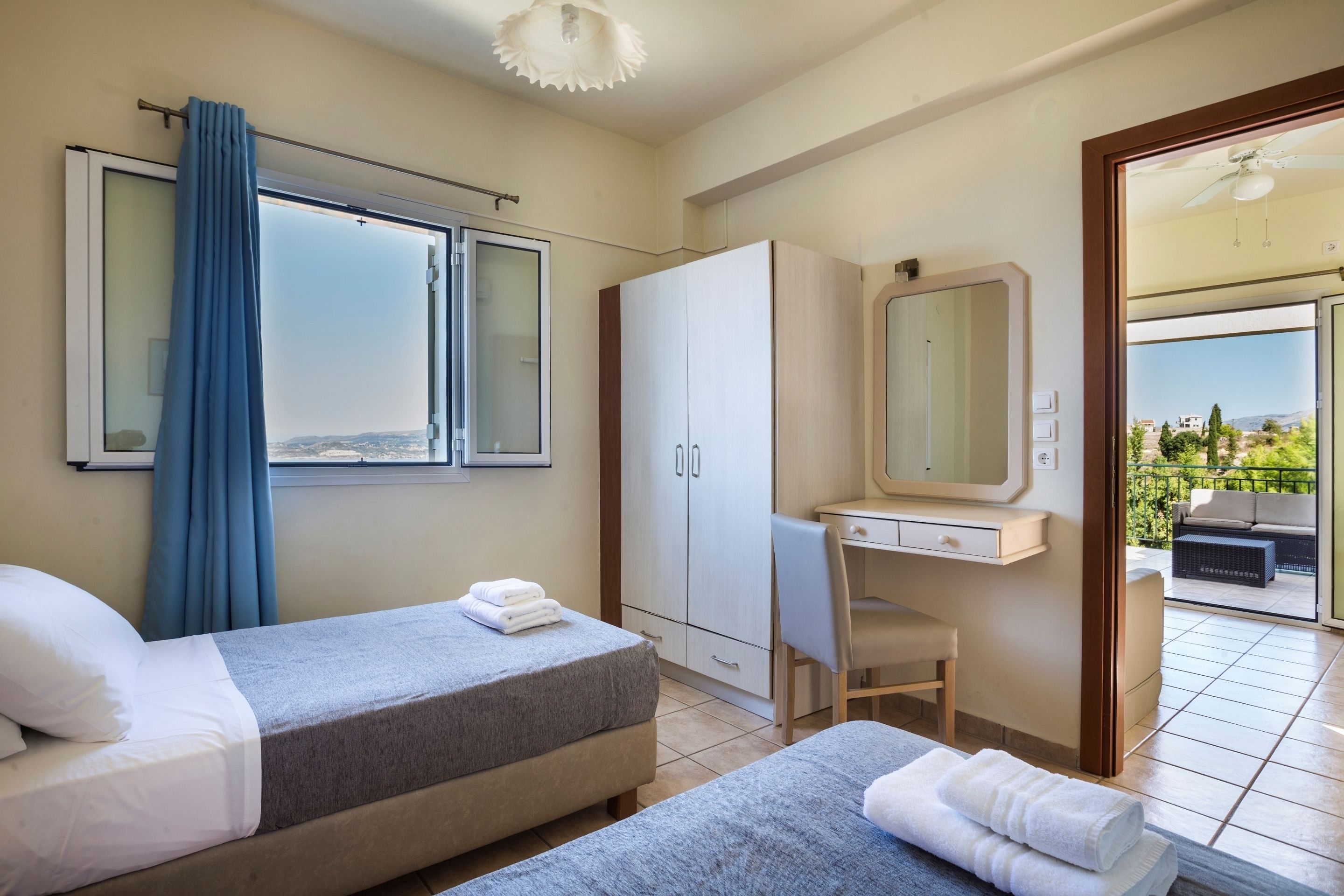 Habitación de hotel con dos camas, un escritorio, un armario y un balcón con vistas.