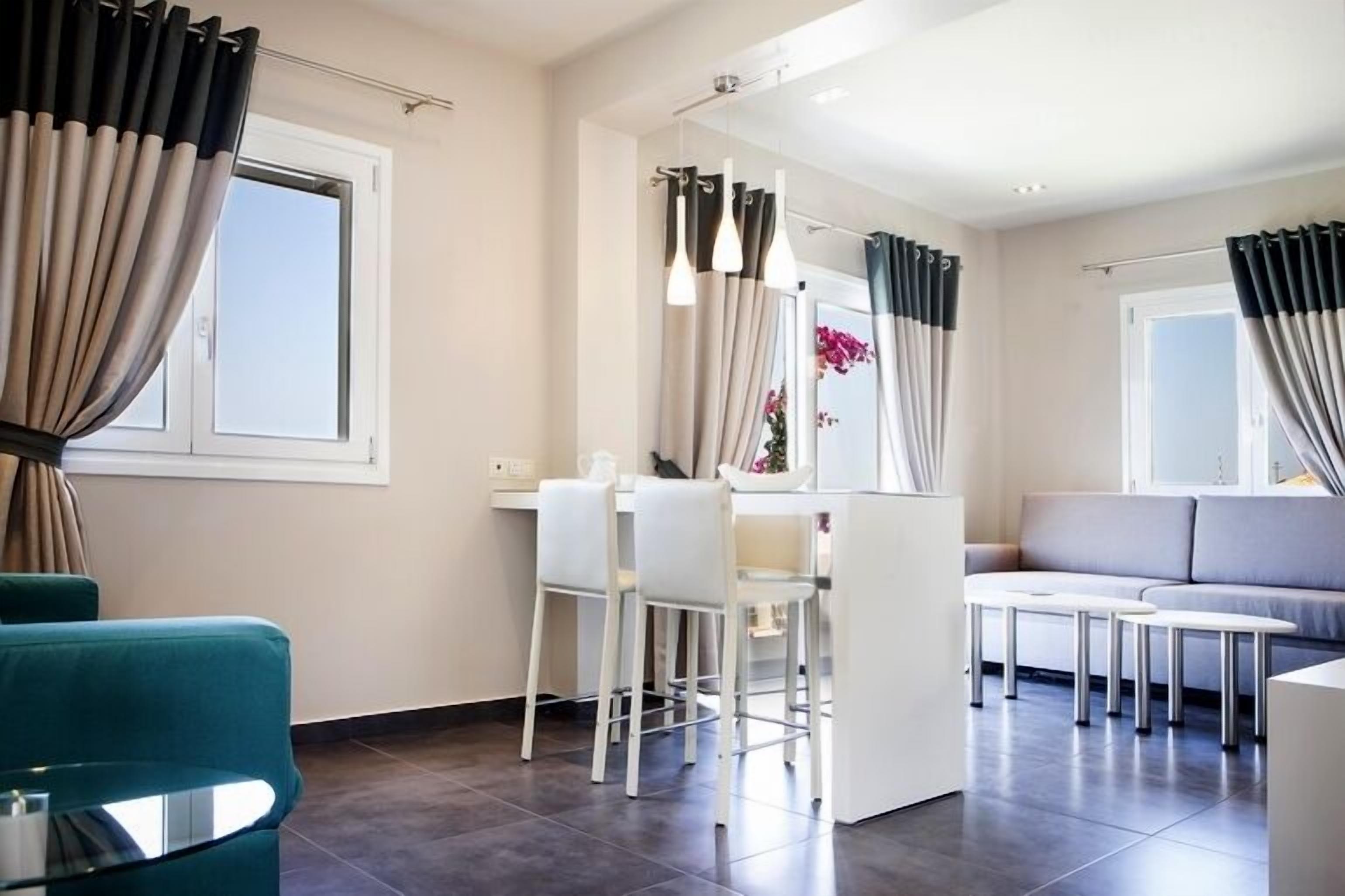 Un salon moderne comprenant un canapé, un coin repas avec des chaises et un espace cuisine avec un comptoir et des chaises.