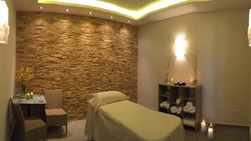 Relax in this serene spa room featuring a plush bed, a wicker chair, and a soothing ambiance.