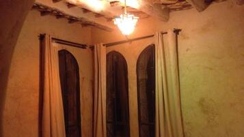 Ein Zimmer mit drei Rundbogenfenstern, einem Bett und einer Chandelüster.