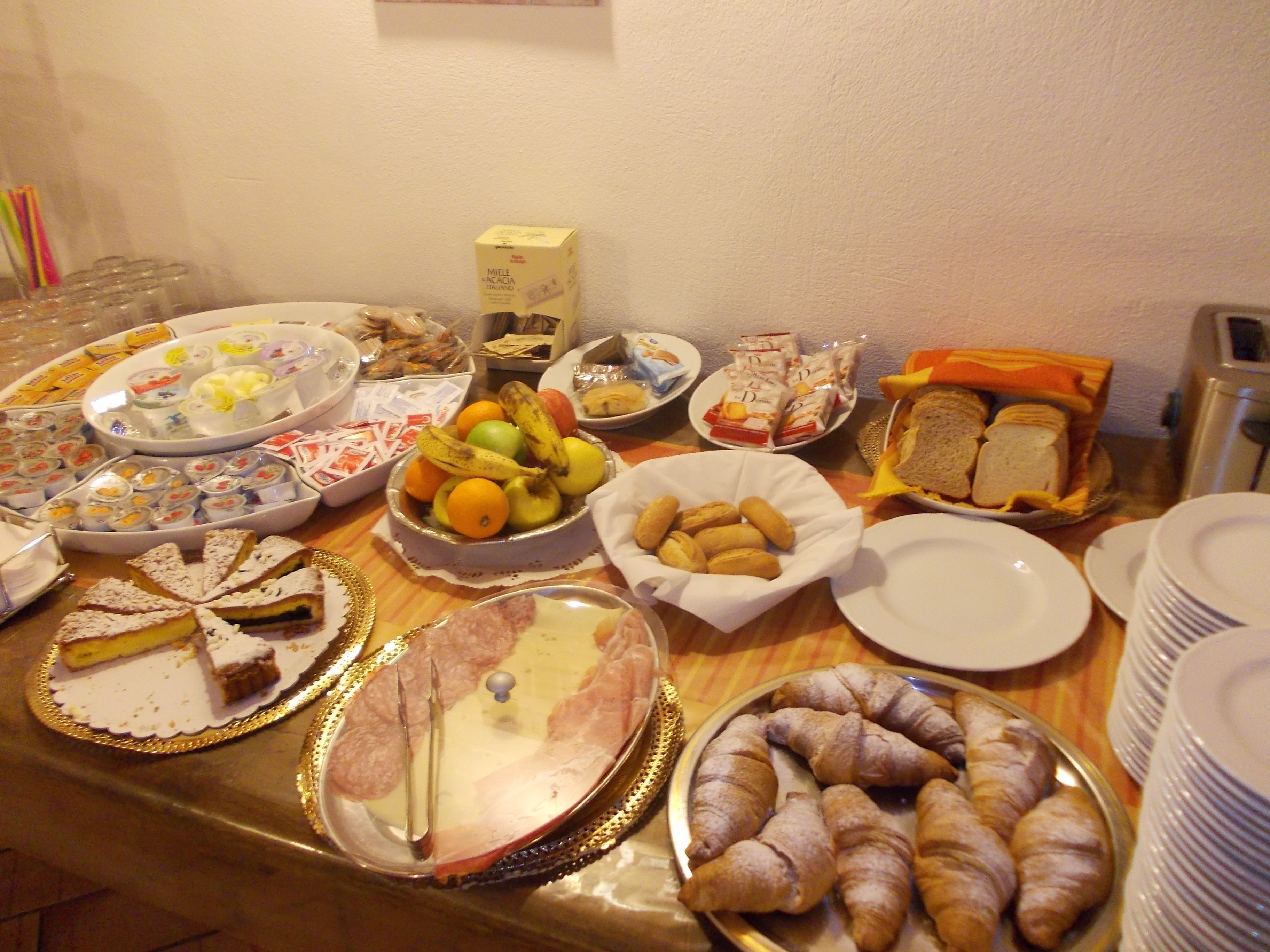 Ein reichhaltiges Buffet mit verschiedenen Speisen, darunter Gebäck, Obst und Sandwiches.